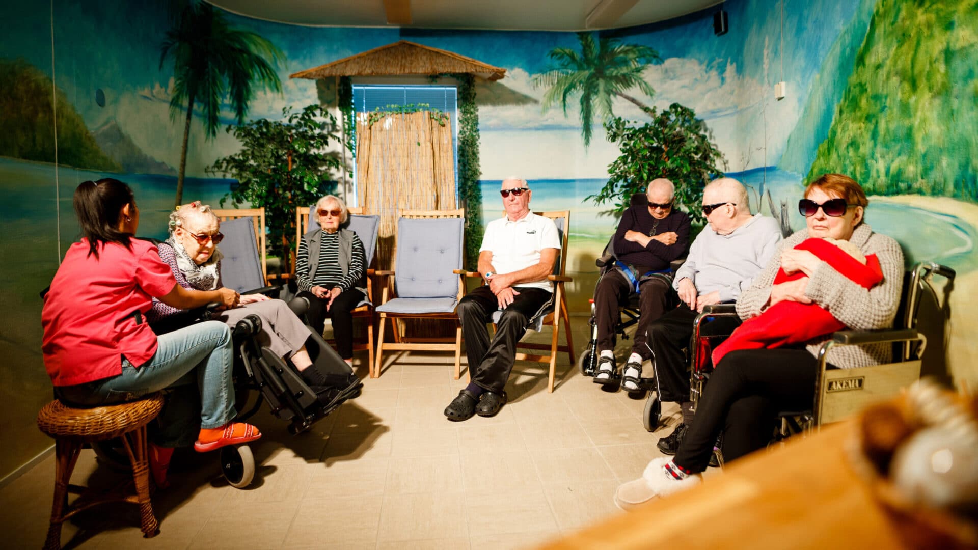 En grupp pensionärer som sitter och solar i ett speciellt solrum på Edestrand Äldreboende.