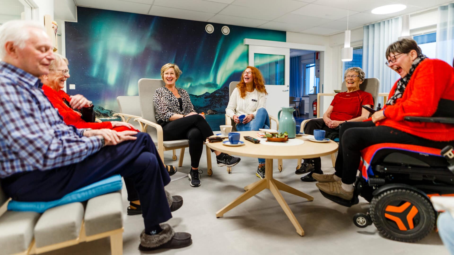 Boende och personal på Å-center trygghetsboende som sitter runt ett bord och skrattar tillsammans.