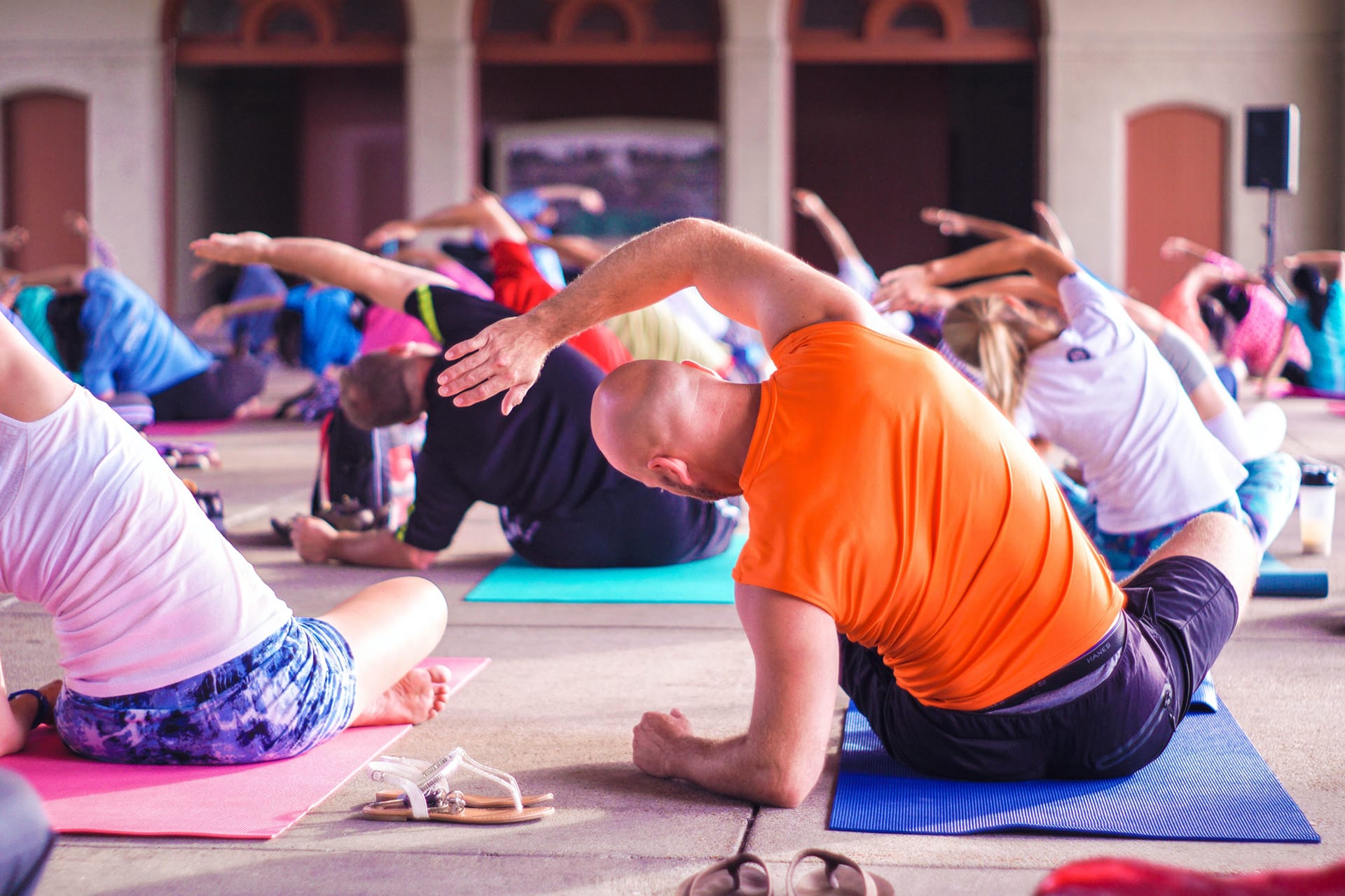 En hel träningssal fylld med människor som sitter på yogamattor och stretchar kroppen.