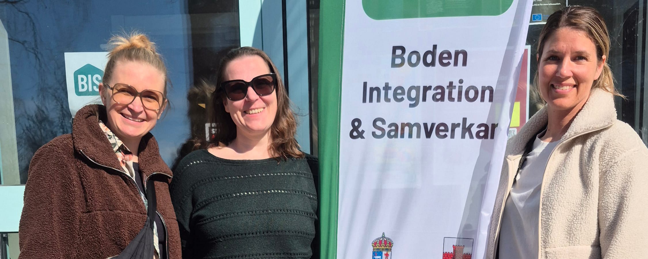 Tre kvinnor står framför en flagga där det står "Boden integration & samverkan"