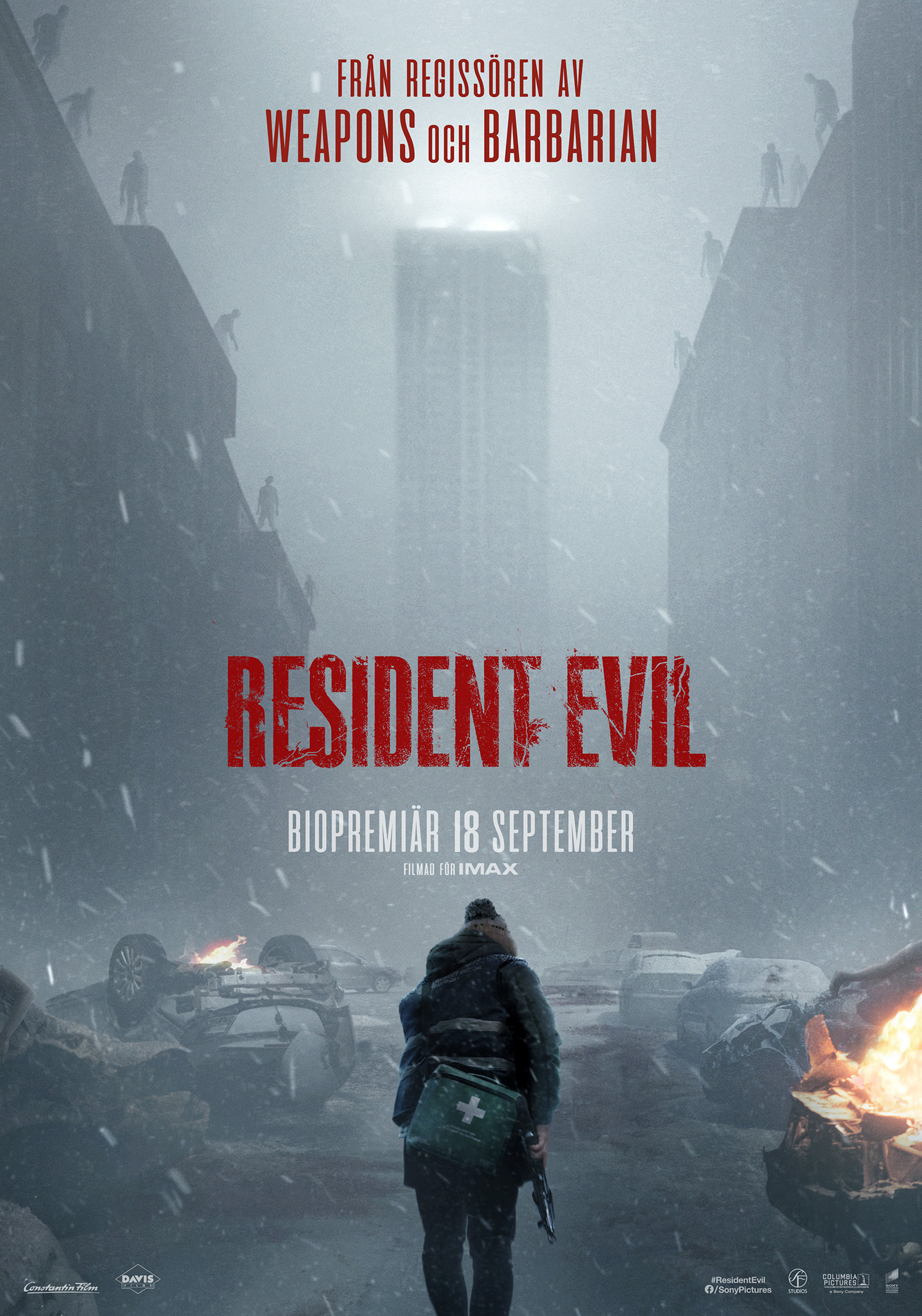 Person with a medical bag walks through a snowy, destroyed city toward a burning wreckage, facing looming red 'RESIDENT EVIL' text at center.