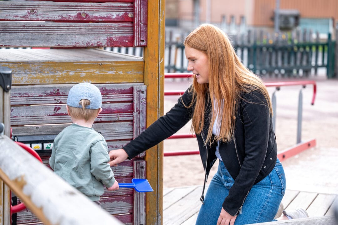 En kvinna och ett litet barn på en lekplats