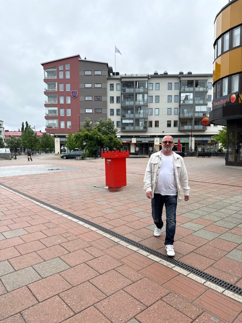 En man går på vägen med hus i bakgrunden